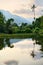 Amazing tropical landscape with lake, palm tree and mountains on sunset