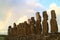 Amazing view of the back of 15 huge Moai statues of Ahu Tongariki with the rainbow on cloudy sky in background