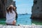 Amazing view of a brunette girl sitting on the Stiniva beach in Croatia, looking at the camera. Beautiful blue adriatic sea,