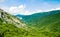 Amazing view of the emerald mountains, hills and ridges covered with green forests. Clear sunny day, blue sky with white clouds.