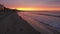 Amazing view of a fiery sunrise with multicolored clouds. Sea waves along the seashore at sunrise