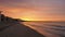 Amazing view of a fiery sunrise with multicolored clouds. Sea waves along the seashore at sunrise