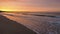 Amazing view of a fiery sunrise with multicolored clouds. Sea waves along the seashore at sunrise