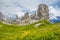 Amazing view of `The Five Pillars` Italian: Cinque Torri  with blooming meadows: fresh green grass and yellow flowers, Dolomites