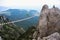 Amazing view of the high rope bridge with traveler above abyss against the Black Sea coast. Scenery of Crimea in summer