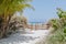Amazing view of the path from tropical garden leading through the gates toward white sand beach and azure tranquil ocean