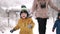 Amazing view of toddler boys and mom walking in winter forest with snowfall background. Babies rejoices first snow