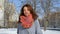 Amazing young woman in coat and colorful knitted scarf posing looking at the camera during sunny day on blue sky