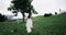 Amazing young woman with pretty long dress running in the middle of green field