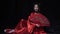 Amazing young woman sits on the floor in red japanese national dress with a fan