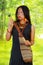 Amazonian exotic woman with facial paint and black dress, natural bag hanging across upper body, pulling out blowgun