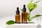 Amber cosmetic bottles with pipette on white podium, product packaging with natural ruscus branch, anti aging serum with peptides