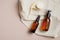 Amber glass bottles with body lotion and shampoo and facial cleansing brush on beige background. Skin care concept