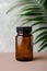 Amber glass supplement bottle and tropical green leaf. Medical package for pills, capsule, drugs. Herbal medicine concept