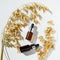 Amber glass vials with a pipette and a sprig of oats on a white background.