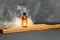 Amber spray bottle with facial cosmetics on a tray on a dark background with smoke