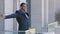 Ambitious African American man employee taking break from work in office. Millennial standing on balcony, looking