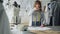 Ambitious creative female tailor is placing garment sketches on studio desk and shooting them with smartphone
