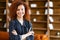 Ambitious smiling young curly woman standing in the office space with her arms crossed