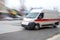 An ambulance responding to emergency call driving fast on street in motion blur