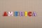 America word on paper background composed from colorful abc alphabet block wooden letters, copy space for ad text