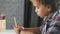 American african boy is sitting at table in classroom and doing homework in education notebook