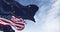 American and Alaskan flags wave in the wind against a blue sky