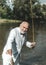 American angler fishing. Still water trout fishing. Handsome mature fisherman in white suit fishing in a river with a