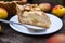 American apple Tsvetaevsky jellied open pie piece on a plate, close-up, on a dark wooden background. Flat lay