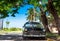 American black 1955 classic car parked under palms in the side street in Havana City Cuba -