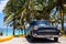 American black classic car parked under palms