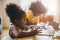 American Black preschool daughter kids doing homework learning education with her sister living together at home
