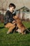 American boule puppies for a walk in the park. Cute Asian toddler sitting on the grass, playing with a few puppies