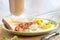 American breakfast with sunny side up eggs, bacon, toast, coffee, green salad, wood background