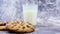 American chocolate chip cookies and milk in a glass glass in the background on a gray background. Traditional round crispy dough w