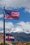 American and Colorado Flag waving in the wind with mountains in