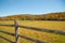 From American country road a rural landscape with farmhouse in distance beyond rustic post and rail fence in Kent county