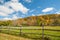 From American country road a rural landscape with red barn in distance beyond rustic post and rail fence in Kent county