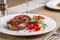 American cuisine. Beef steak with red bbq tomato sauce and cherry tomatoes. A glass of cool wine. Serving dishes on a white plate