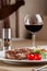 American cuisine. Beef steak with red bbq tomato sauce and cherry tomatoes. A glass of cool wine. Serving dishes on a white plate