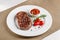 American cuisine. Beef steak with red bbq tomato sauce and cherry tomatoes. A glass of cool wine. Serving dishes on a white plate