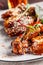 American cuisine concept. Fried glazed chicken legs with sesame on a white plate with chilli peppers. Background image for a menu