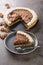 American cutted piece of chocolate walnuts tart with whipped cream close-up in a plate. vertical