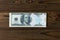 American dollar bill glued with a medical plaster on the background of a wooden table.