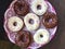 American donuts, glazed with melted chocolate and decorated with sprinkling, lie on a platter