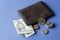 american five dollars bill, coins and brown leather wallet on the blue background