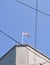 American flag atop building against blue sky crossed by power-lines