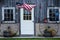 American Flag blowing in the wind by a door and two wagon wheels