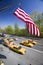 American Flag flies over Central Park in spring with yellow taxies in front of Helmsely Park Lane, Manhattan, New York City, NY