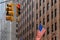 American flag in front of business building with traffic light red New York US